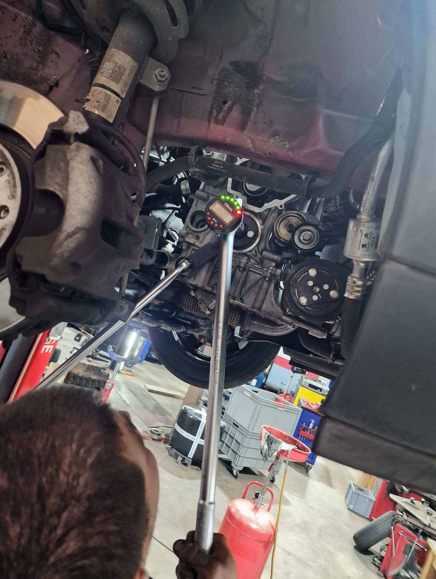 Mécanicien LudoMeca utilisant une clé dynamométrique digitale sous un véhicule sur pont élévateur